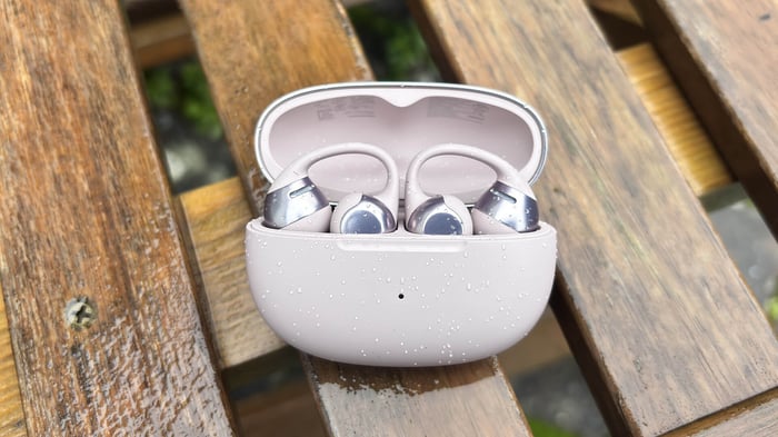 Shokz OpenDots One earbuds on a wooden desk, highlighting microphone placement
