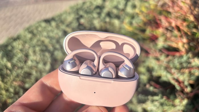 Shokz OpenDots One earbuds on a reflective surface with cityscape backdrop