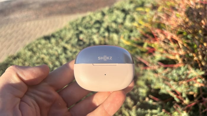 Shokz OpenDots One earbuds and charging case displayed on a sleek surface