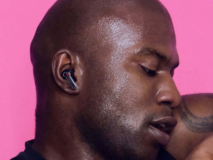 Ear (3a) earbuds angled with charging case on reflective surface
