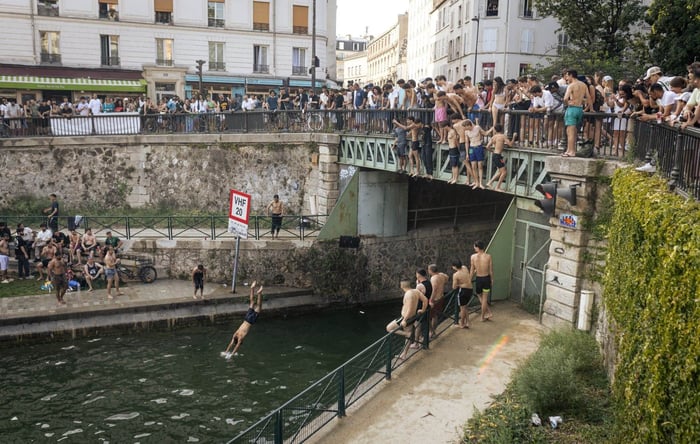 Young people swim in the Canal Saint-Martin in Paris, France during extreme heat