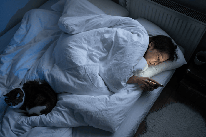 A person lying in bed with a catAI-generated content may be incorrect.