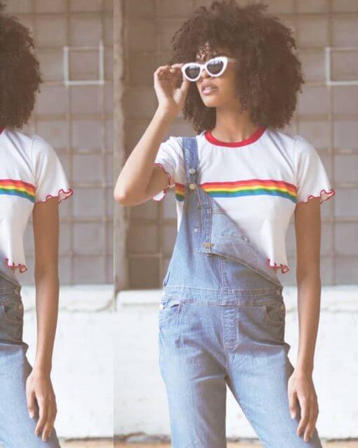 Woman with sunglasses poses in overalls and crop top.