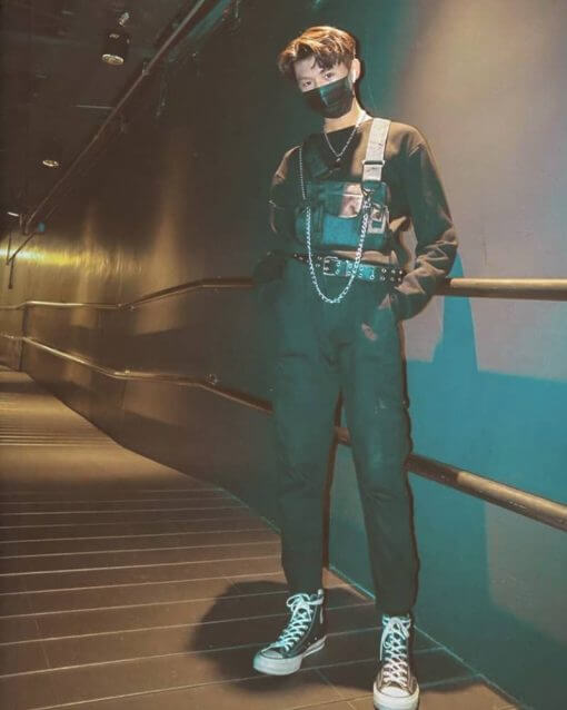 Man in mask wears all black outfit with chains and necklaces.