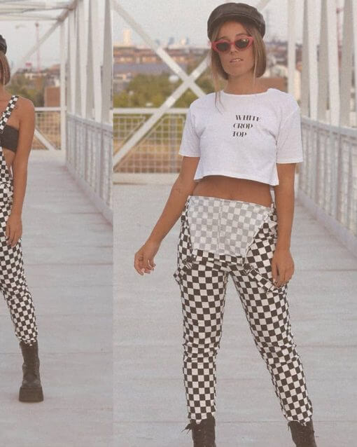 woman wears checker print overalls with bib hanging down.