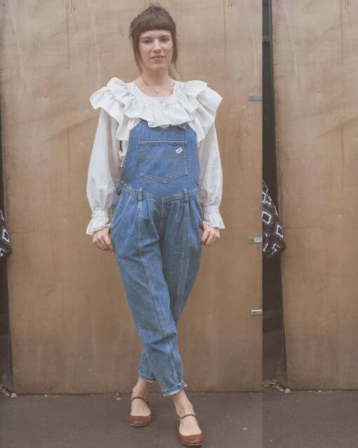 Woman in ruffled collar shirt wears overalls