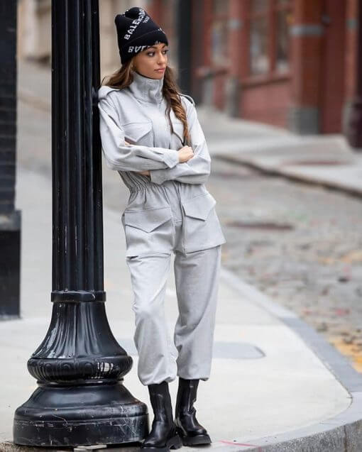 person leaving against a street light wearing a beanie and coveralls