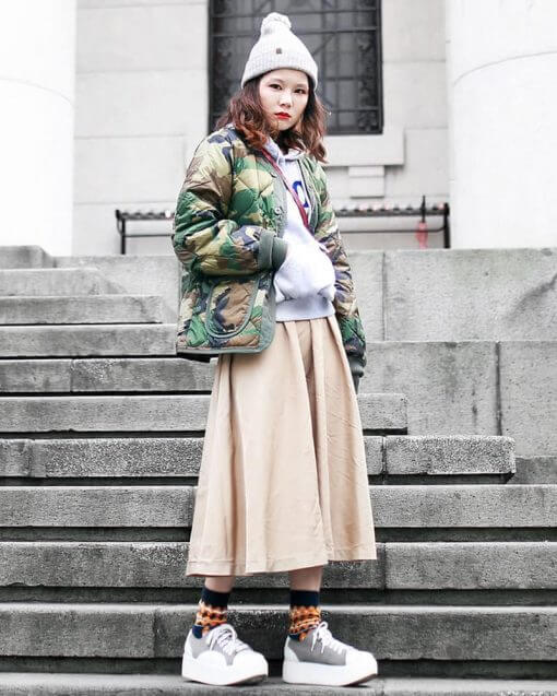 woman standing on stairs wearing a beanie and long skirt