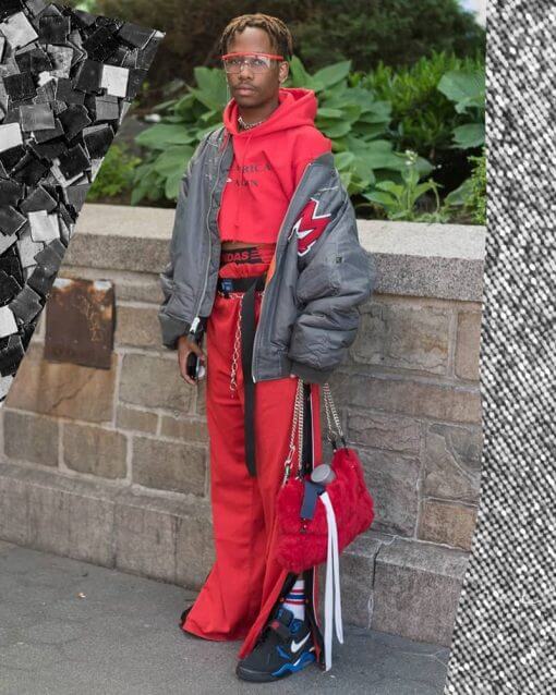Person in New York stands on the sidewalk in many layers, including a cropped red hoodie.
