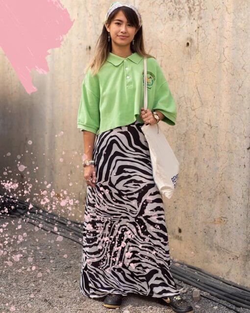 Woman in New York poses in a green cropped polo shirt and long zebra print skirt.