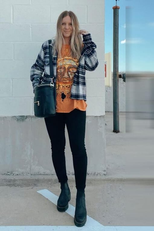 woman wearing flannel shirt over band t-shirt and smiling