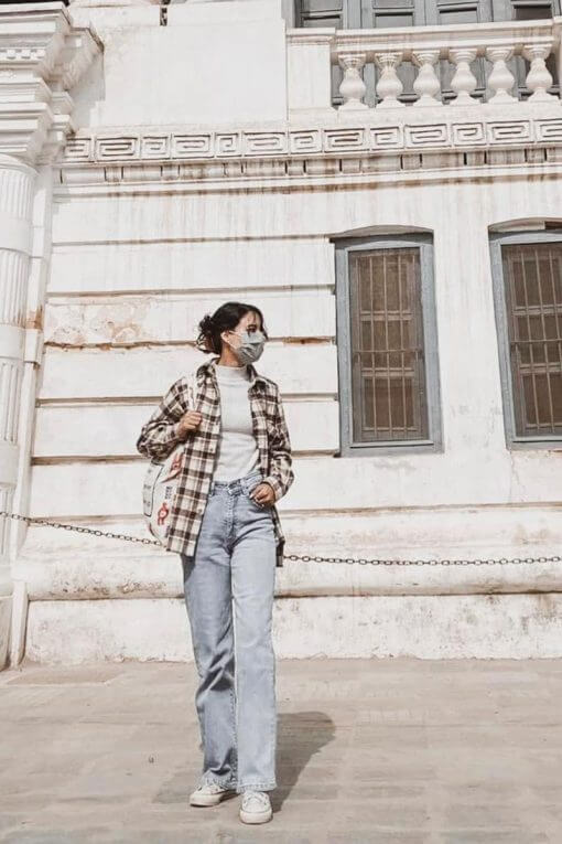 woman wearing lightwash jeans, a flannel shirt, and a face mask