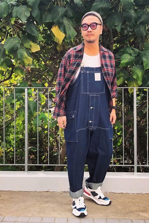 man wearing a flannel shirt over overalls