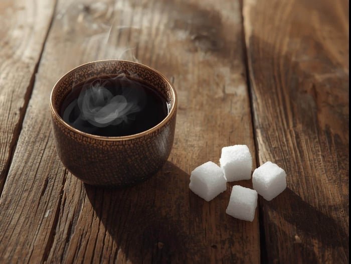 Strong black tea with sugar cubes on a wooden table.