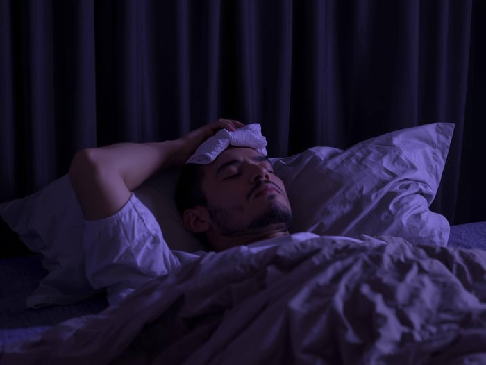  Person resting in dim room with blackout curtains and cool compress