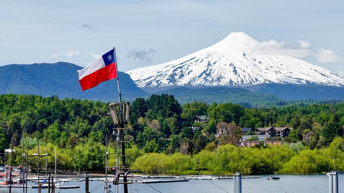 Close-up of the Chilean flag waving in the port of the city of Pucón, with the imposing Villarrica volcano in the background.