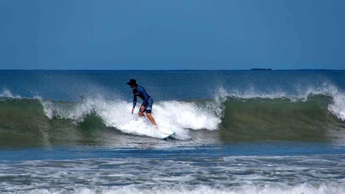 Man surfing off the beach in Tamarindo, Guanacaste, Costa Rica