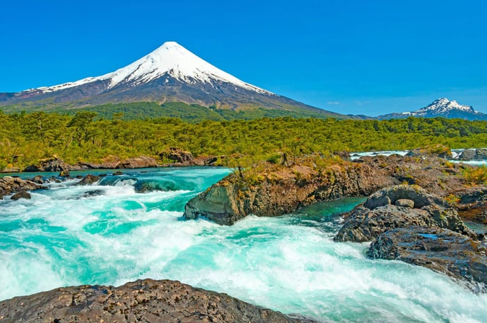 Petrohué Waterfalls (Saltos del Petrohué) in the Vicente Pérez Rosales National Park, with Osorno volcano in the background.