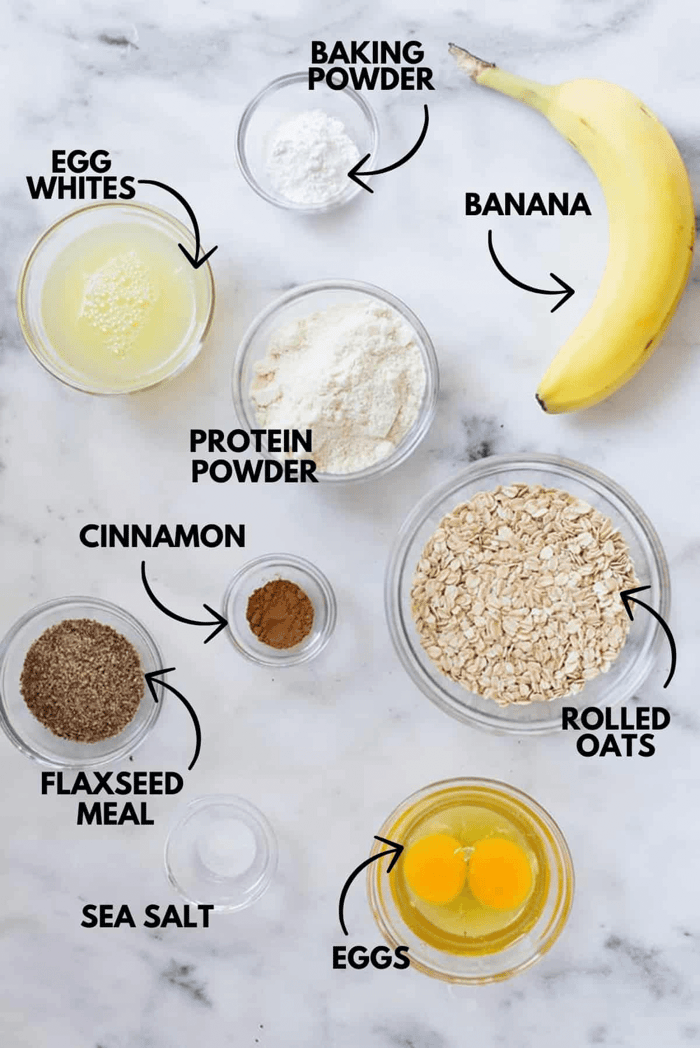 A photo with ingredients for banana protein pancakes laying flat against a white marbled surface.