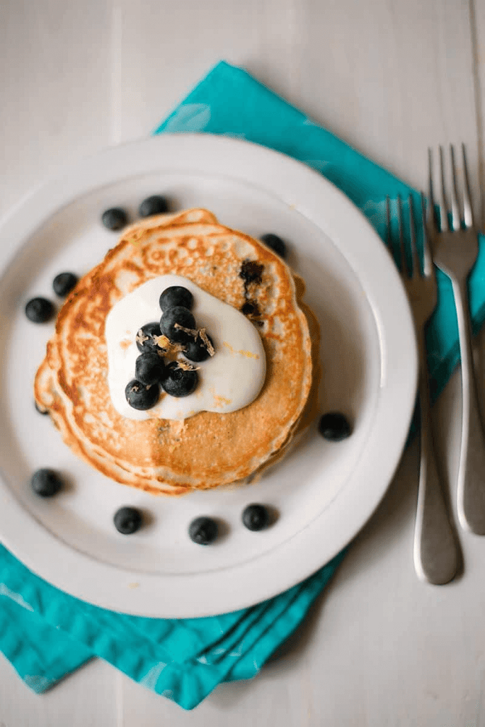 A photo of lemon blueberry protein pancakes on a white plate.