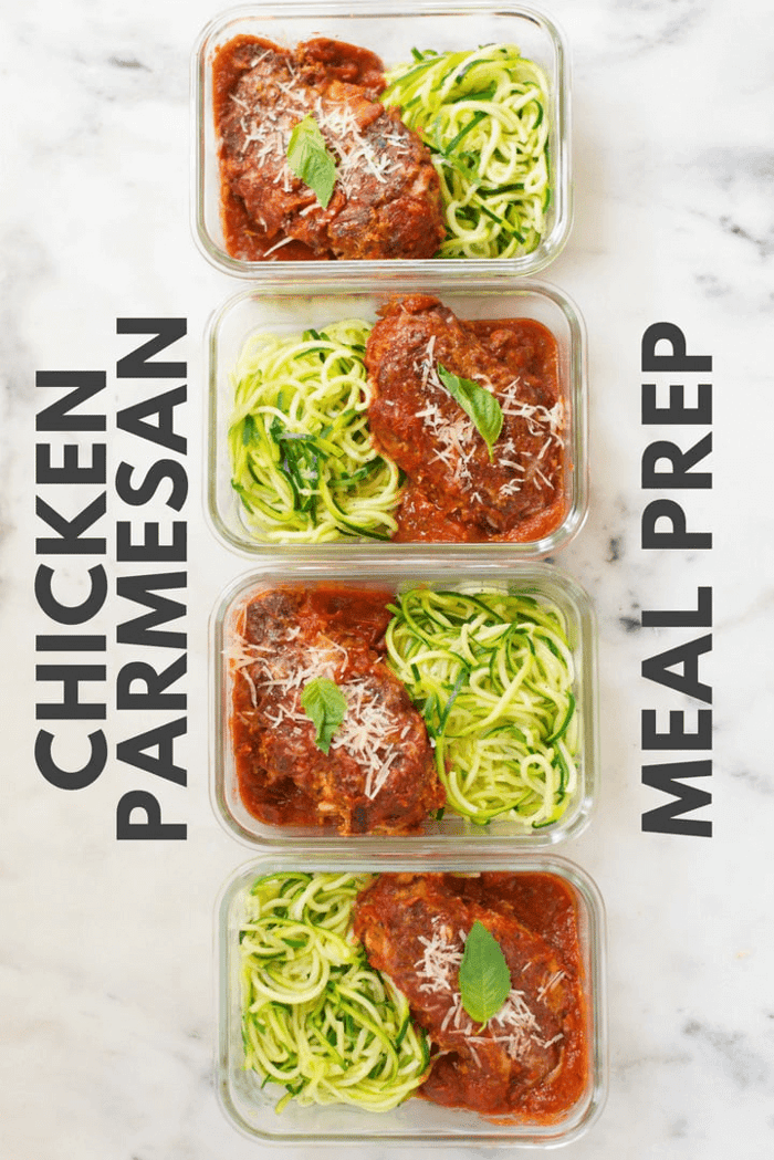Four meal prep containers each containing meal prep healthy chicken parmesan