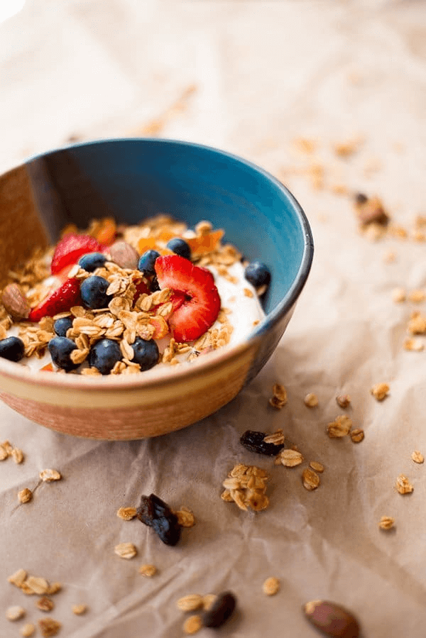 An image of healthy granola recipe on top of a bowl of yogurt ready to be eaten.
