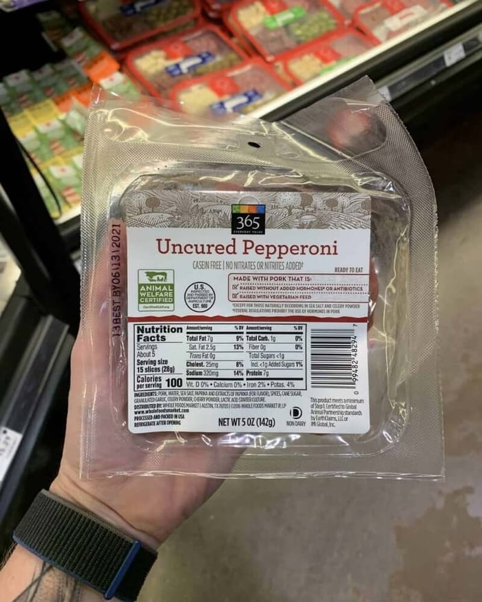 A hand holding a package of deli meat branded 365 Whole Foods Market | Uncured Pepperoni.
