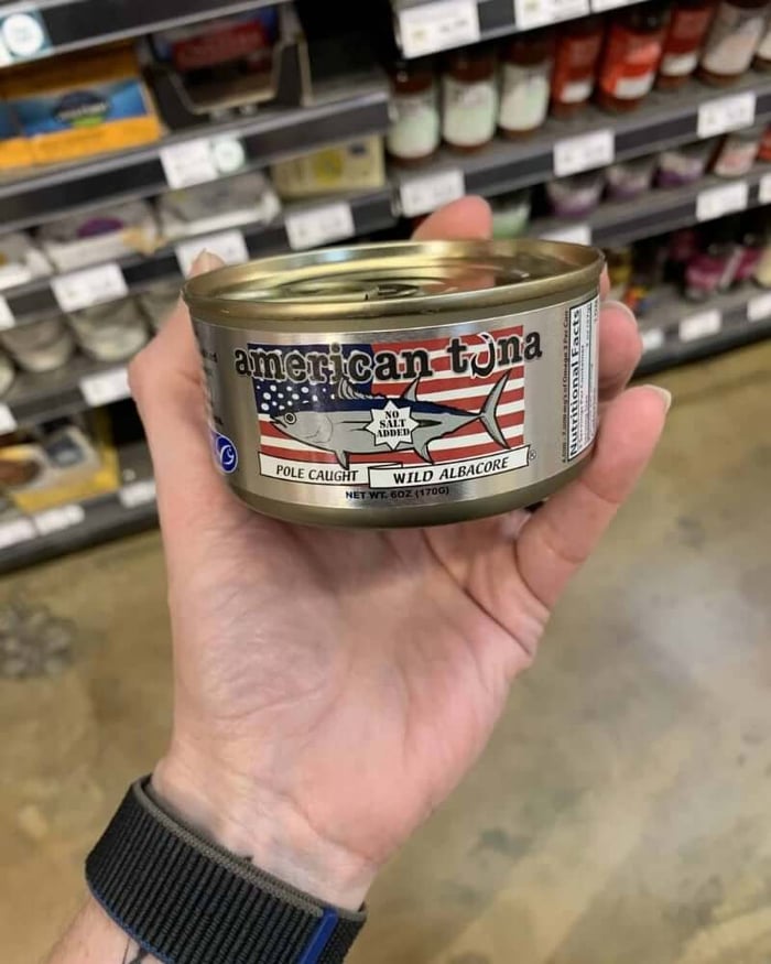 Hand holding a tuna can labeled American Tuna.