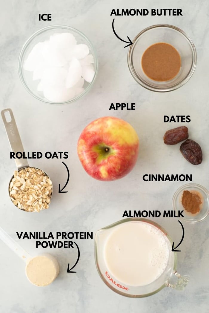 Ingredients for apple crisp protein smoothie laying flat against a white marble surface.