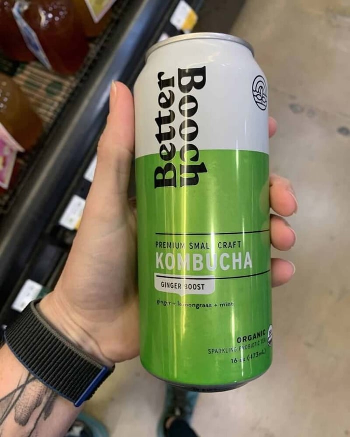 A photo of a hand holding a kombucha bottle labeled Better Booch Kombucha.