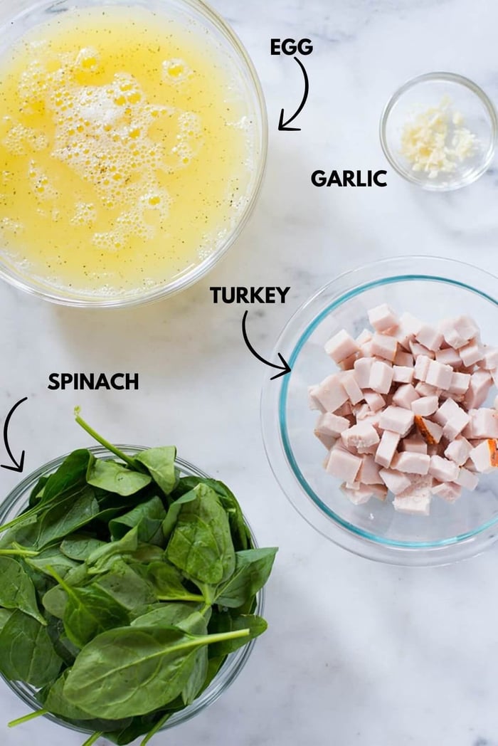 A photo of ingredients for egg white spinach scramble meal prep laying flat against a marble table.