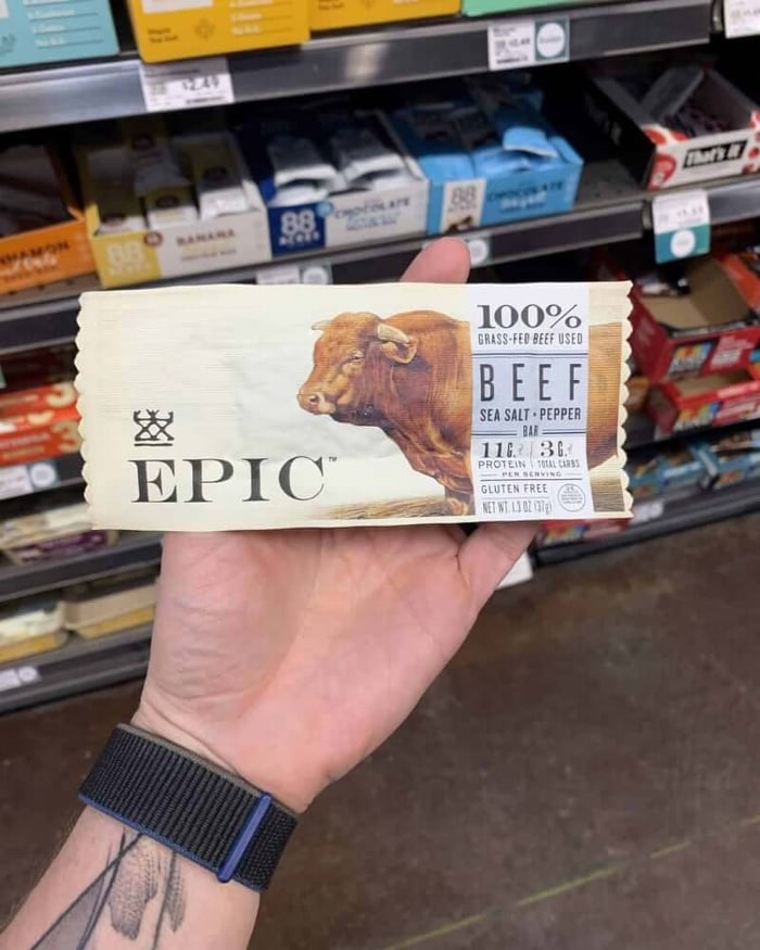 A hand holding a protein bar from the brand Epic.