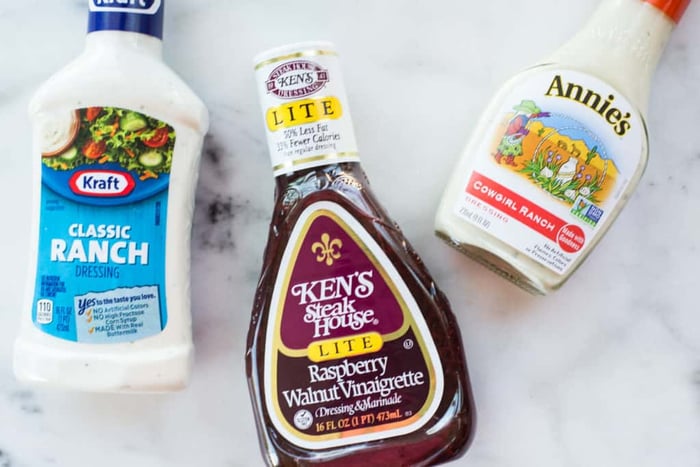 Overhead view of three bottles of salad dressing that may contain Vegetable or seed oils that can cause inflammation.