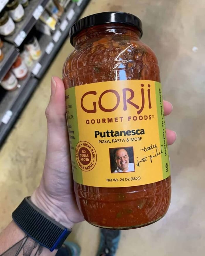 A hand holding a jar of pasta sauce branded by Gorji.