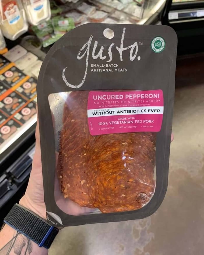 A hand holding a package of deli meat branded Gusto | Uncured Pepperoni.