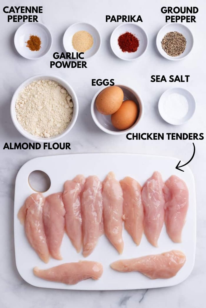 An image of ingredients for healthy chicken nuggets laying flat against a white marble surface.