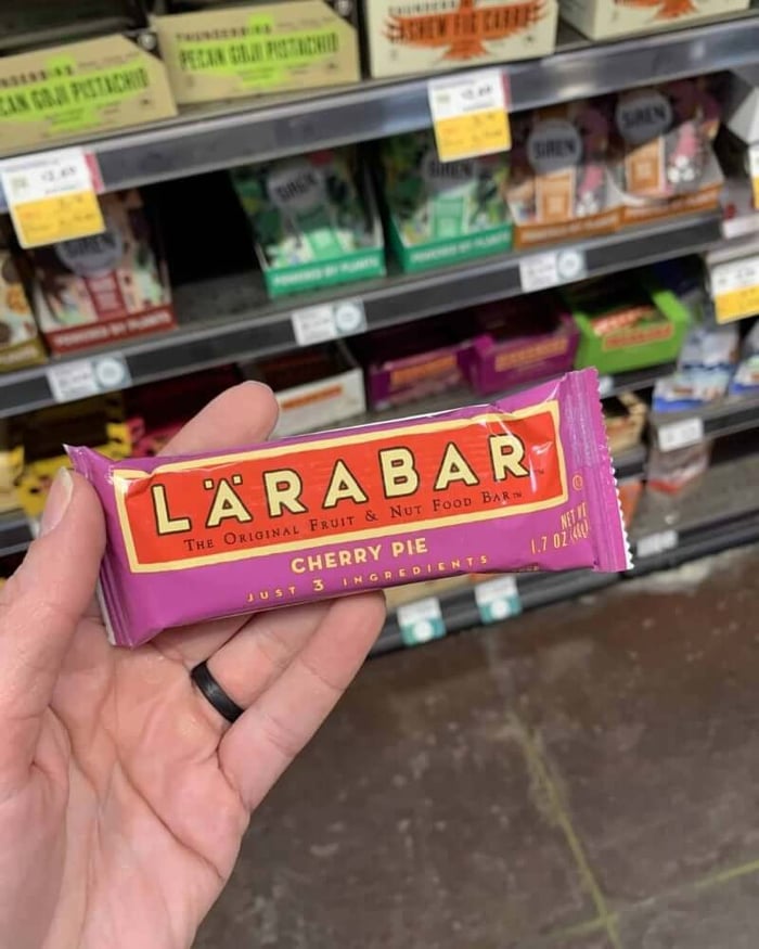 A hand holding a protein bar from the brand Larabar.