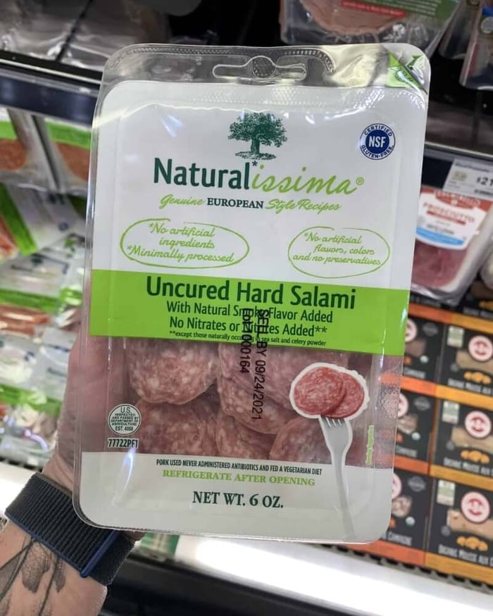 A hand holding a package of deli meat branded Naturalissima | Uncured Hard Salami.