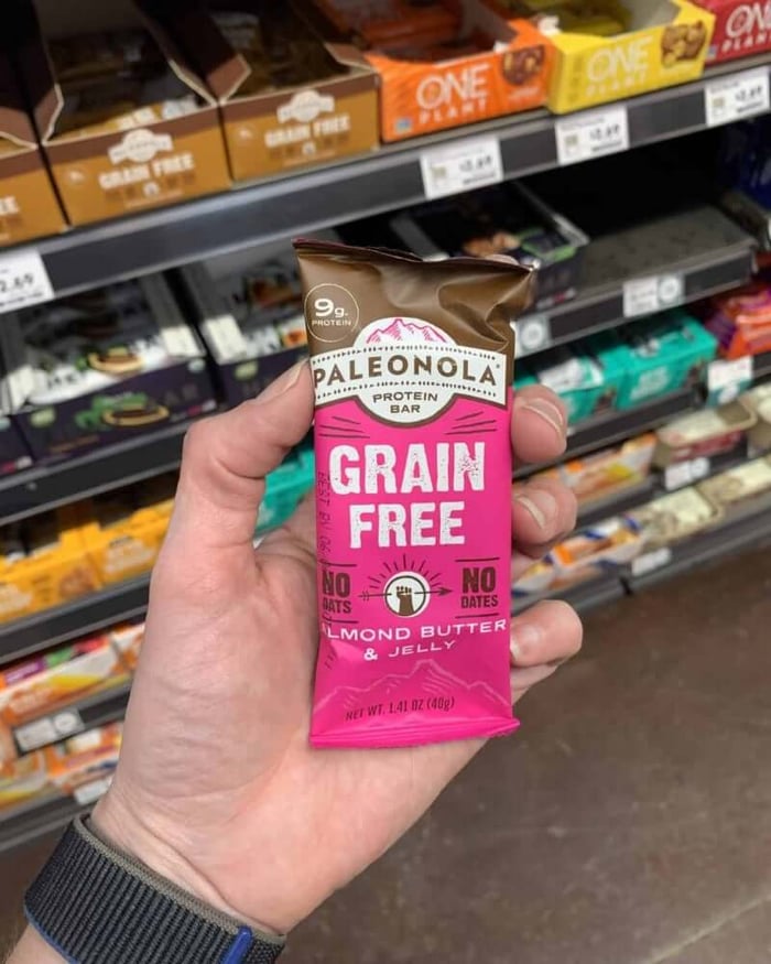 A hand holding a protein bar from the brand Paleonola.