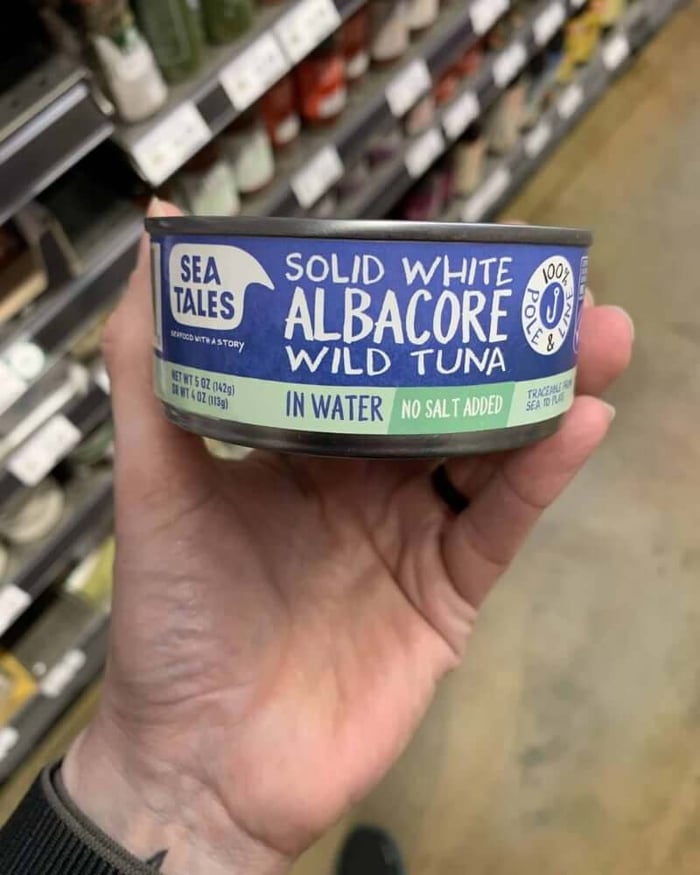 Hand holding a tuna can labeled Sea Tales Tuna.