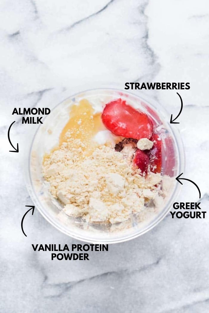 Ingredients for strawberry protein shake all in a blender.