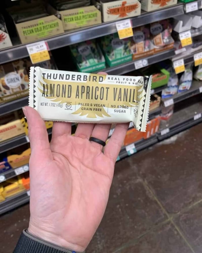 A hand holding a protein bar from the brand Thunderbird.