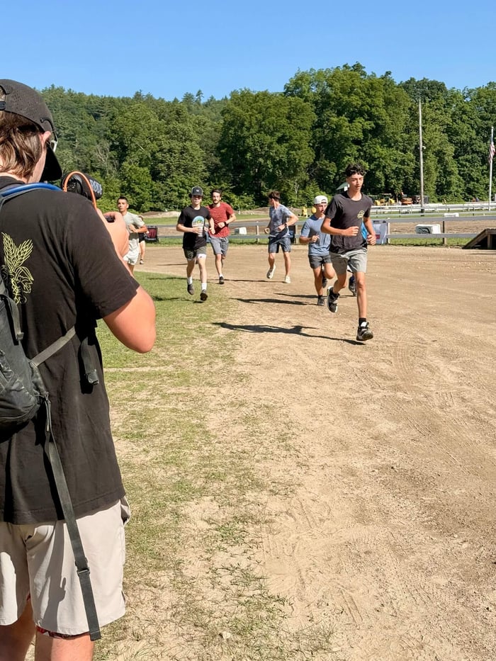 Group of people running on a dirt track with trees in the background