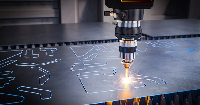 A laser cutting head cutting precise shapes into a metal sheet, with bright sparks and detailed industrial patterns.