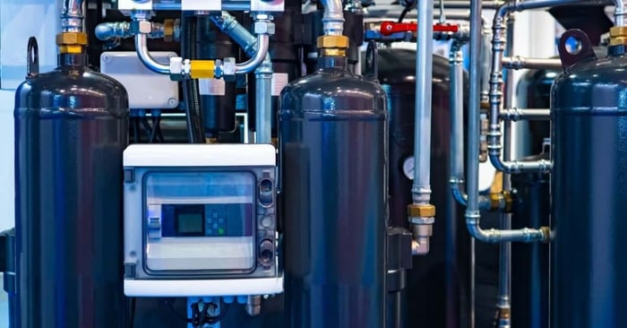 Industrial compressed air system with pressure vessels, gauges, control panel, and interconnected stainless steel piping.