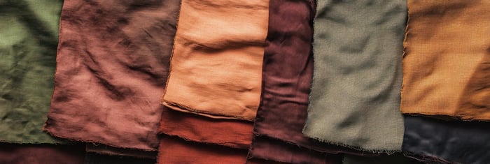 Flat lay of sustainable fabric swatches in neutral tones, showcasing eco-friendly textures and materials for minimalist fashion design.