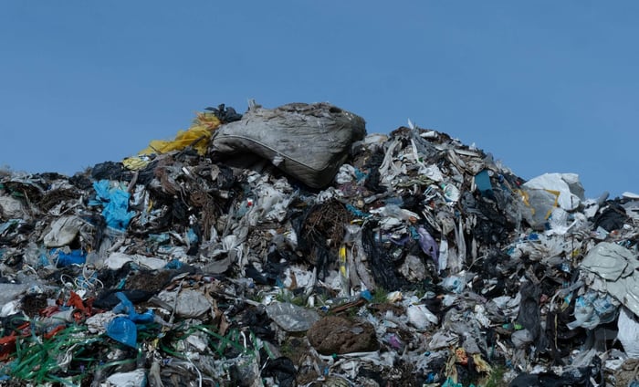 Overflowing landfill piled with discarded clothing, highlighting the environmental impact of fast fashion waste.
