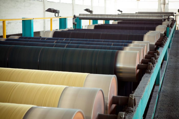 Industrial textile mill dyeing process showing large fabric rolls being colored in eco-friendly dyes.