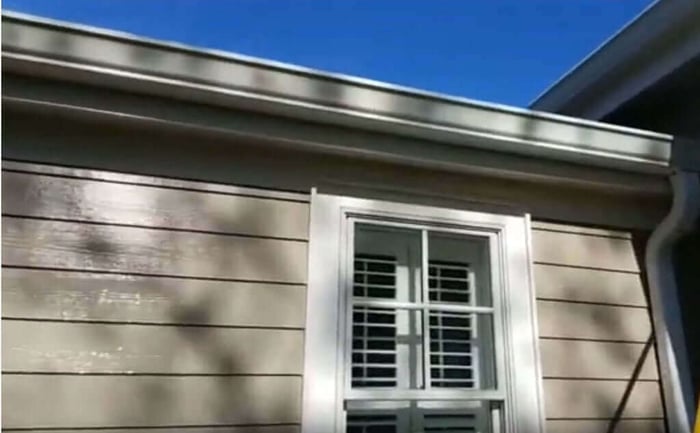 Black tiger stripes on white aluminum gutters before cleaning