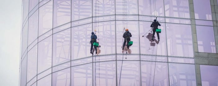 High-rise window cleaner on rope descent system cleaning a glass facade